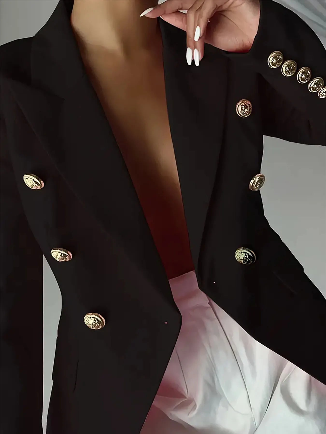 Black blazer with gold-tone coin-style buttons on lapel and cuffs; deep V neckline