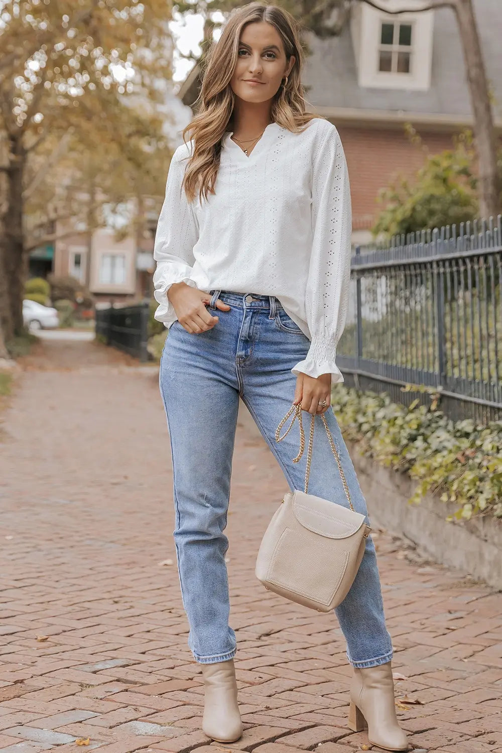 White openwork notched blouse with long sleeves, worn with light blue jeans