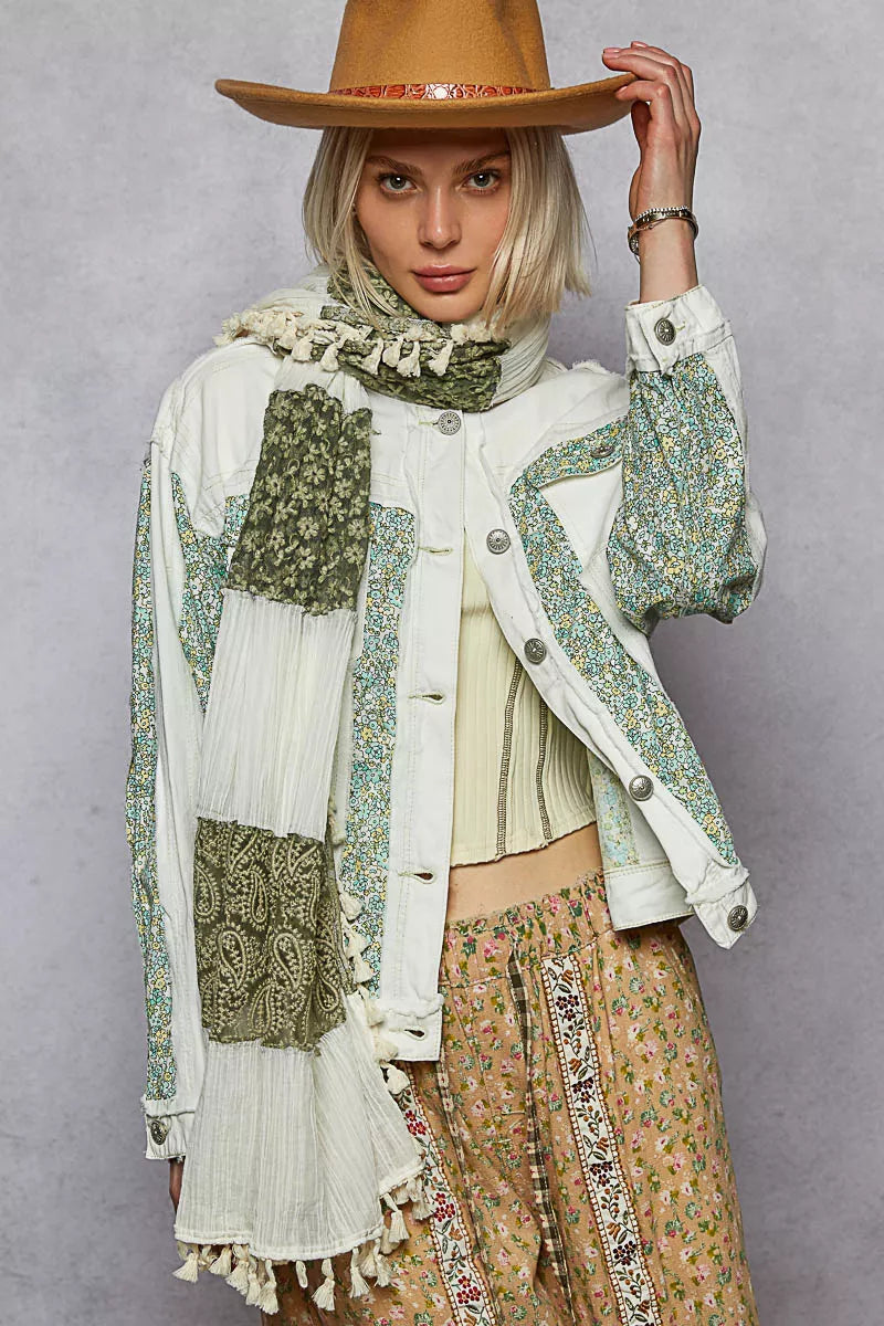 Off-white patchwork denim jacket with green floral sleeves, button front, tassel hem