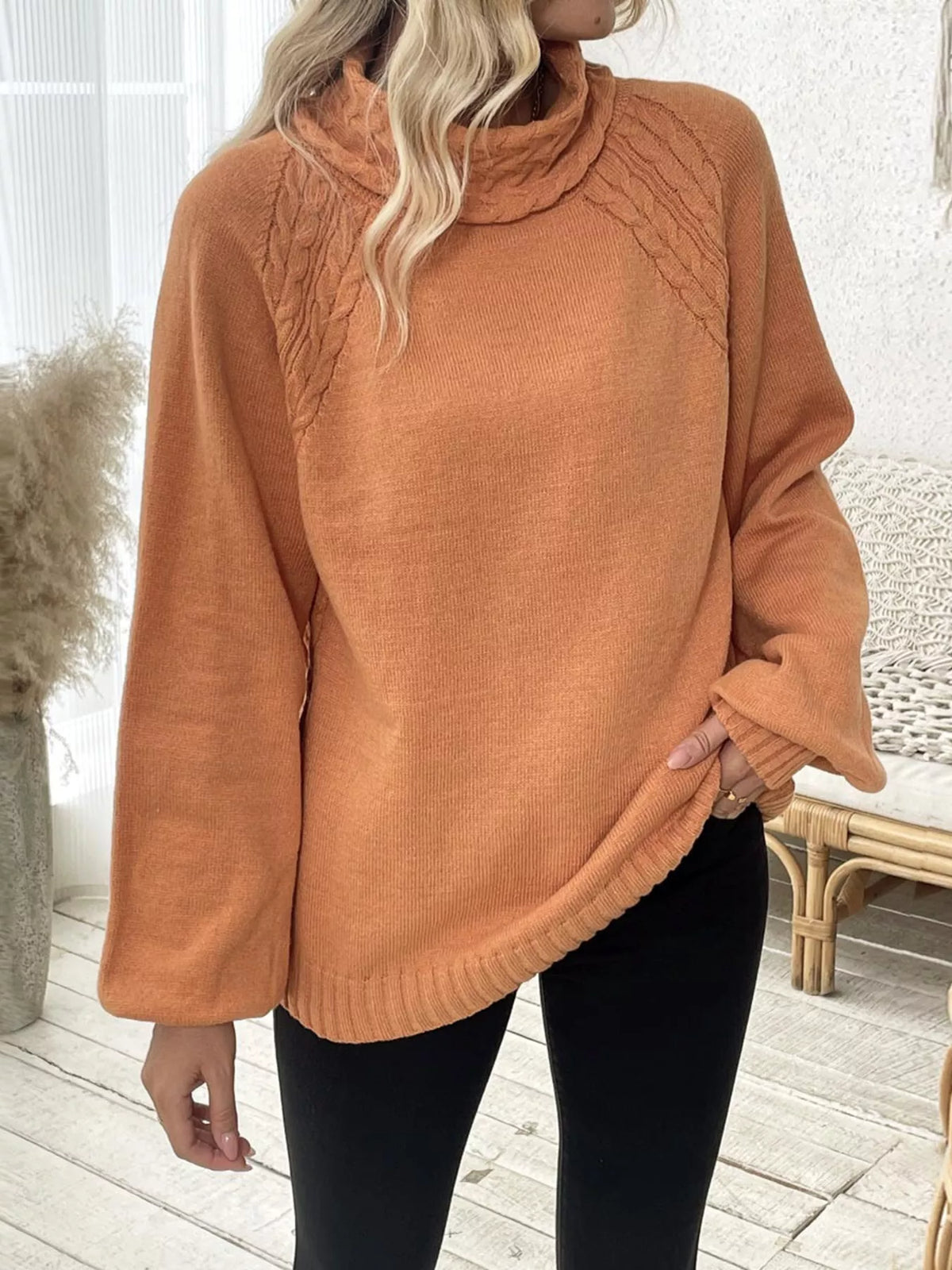 Tangerine cable-knit turtleneck sweater with long sleeves and cable knit texture