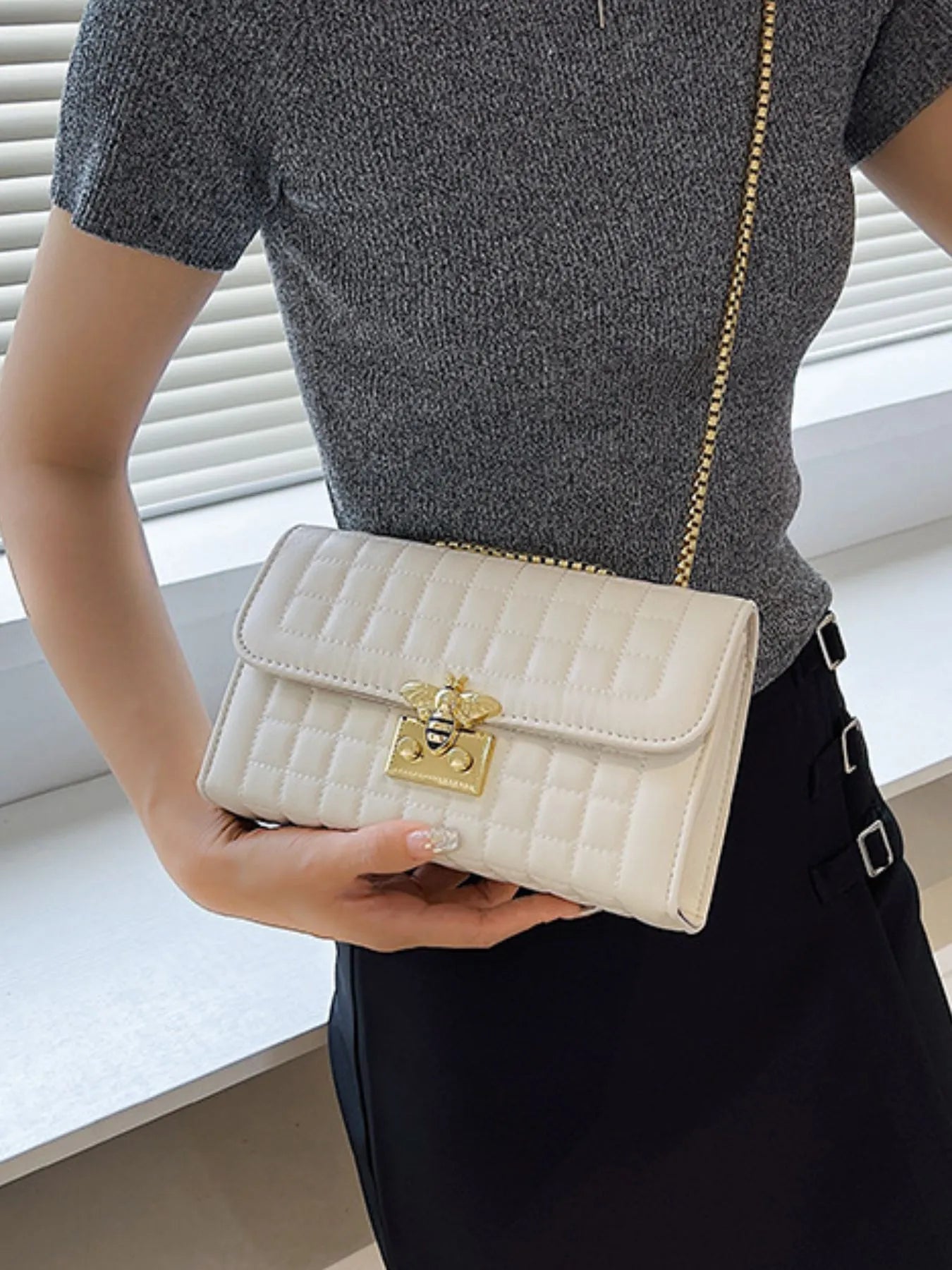 Beige quilted shoulder bag with gold chain strap and bee clasp, flap front