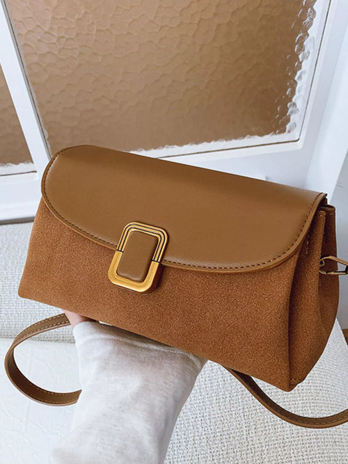 Brown flap crossbody bag with gold-tone buckle clasp and long shoulder strap