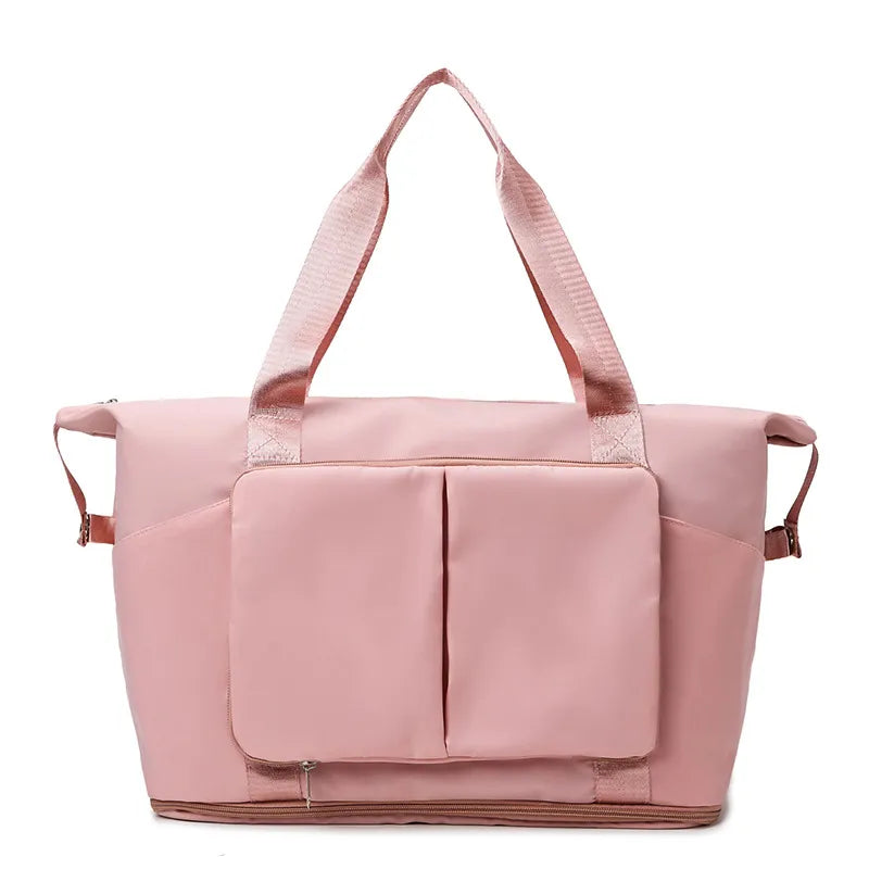 Dusty pink travel duffel bag with front organizer pocket, top handles, and side carry straps.