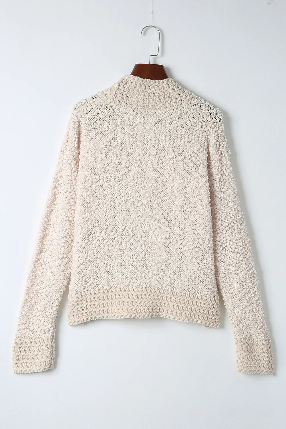 Cream open-front cardigan hanging on a hanger, textured knit with long sleeves