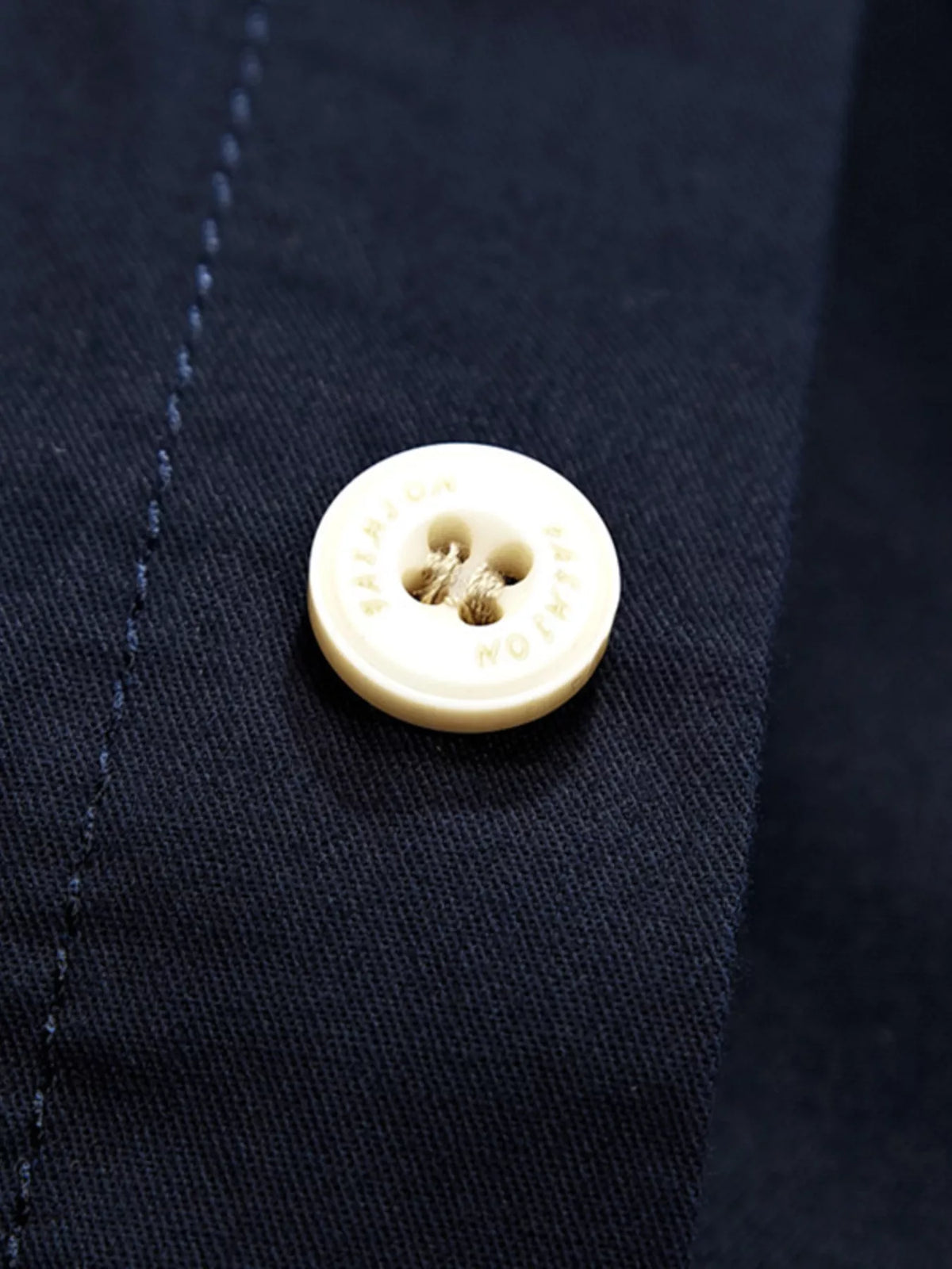 Navy shirt fabric and front button with visible stitching detail