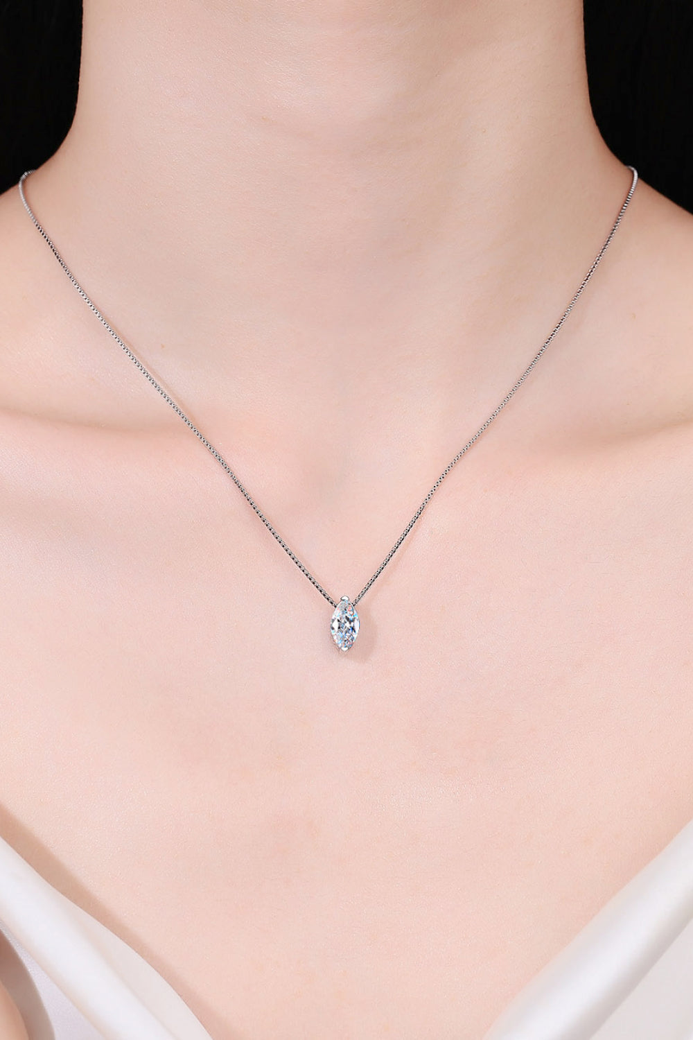 Sterling silver moissanite pendant necklace resting on neckline, small marquise stone