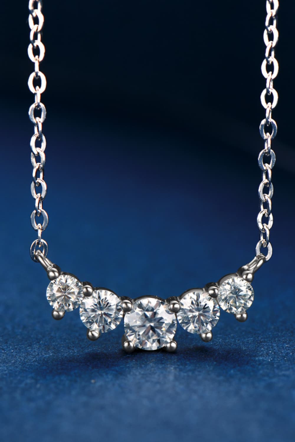 Silver pendant necklace with five round and oval sparkling stones in a row