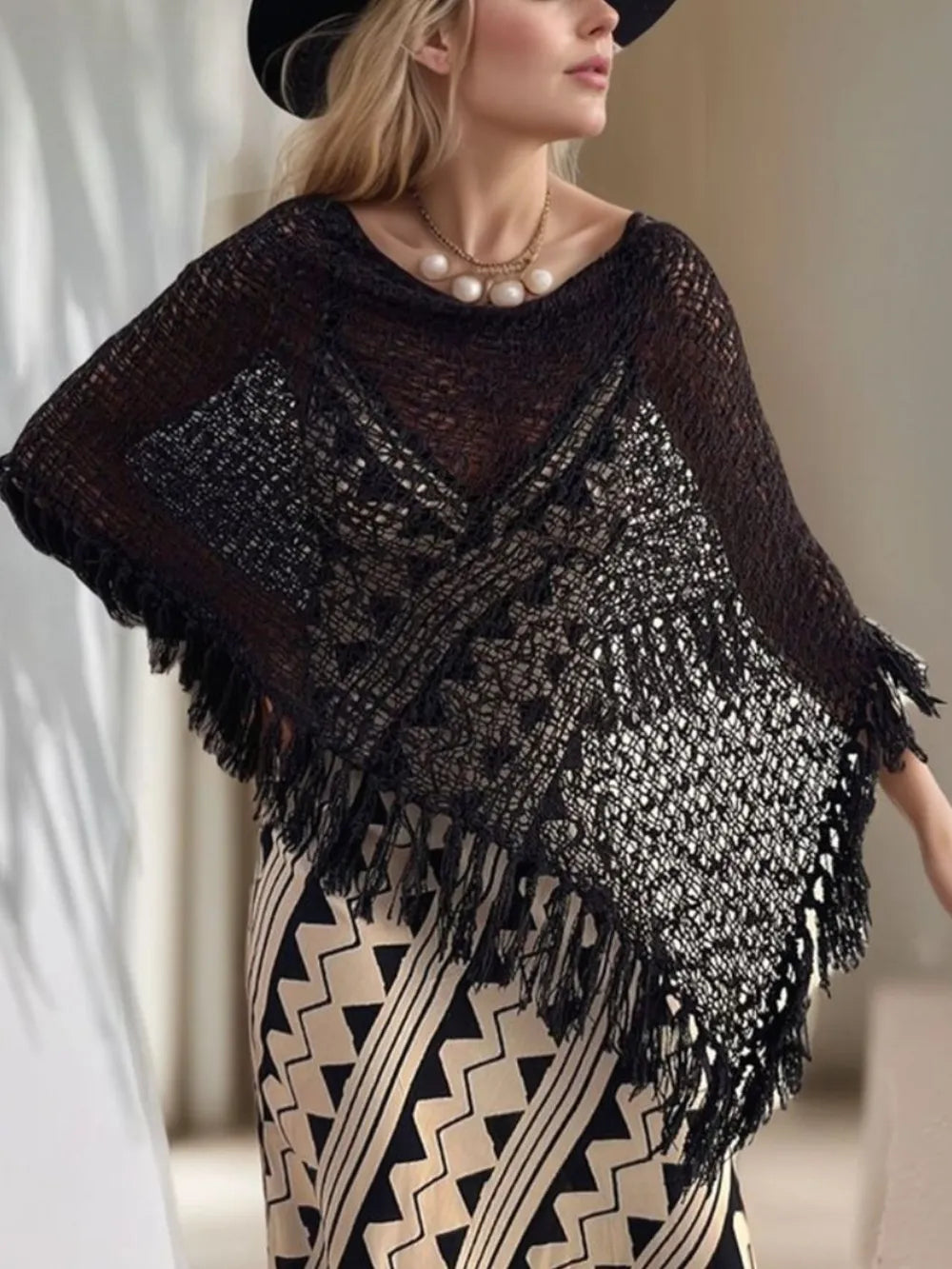 Black open-knit shawl with boat neck and fringed edges on sleeves