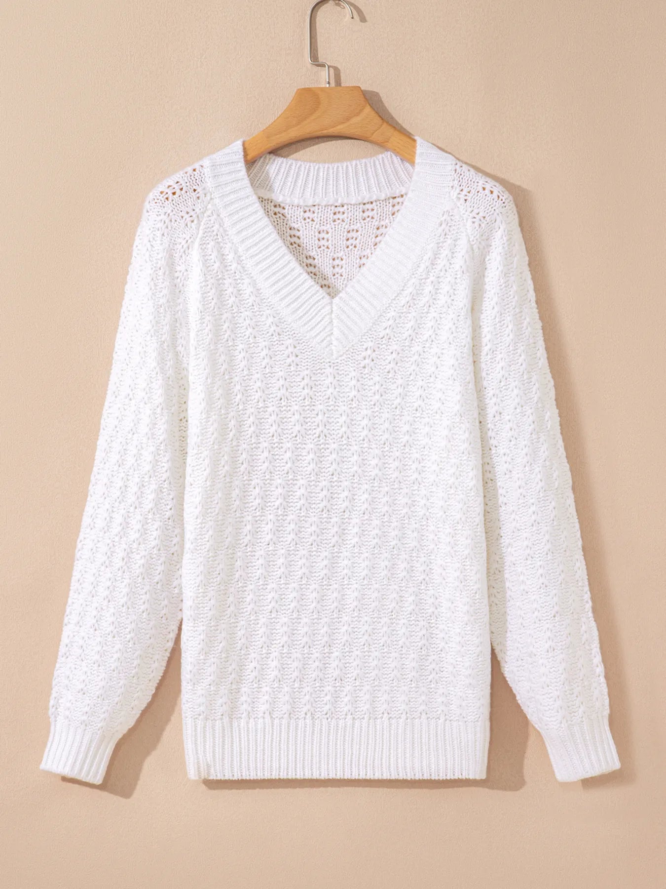 White textured knit V-neck sweater on hanger, long sleeves and ribbed hem.