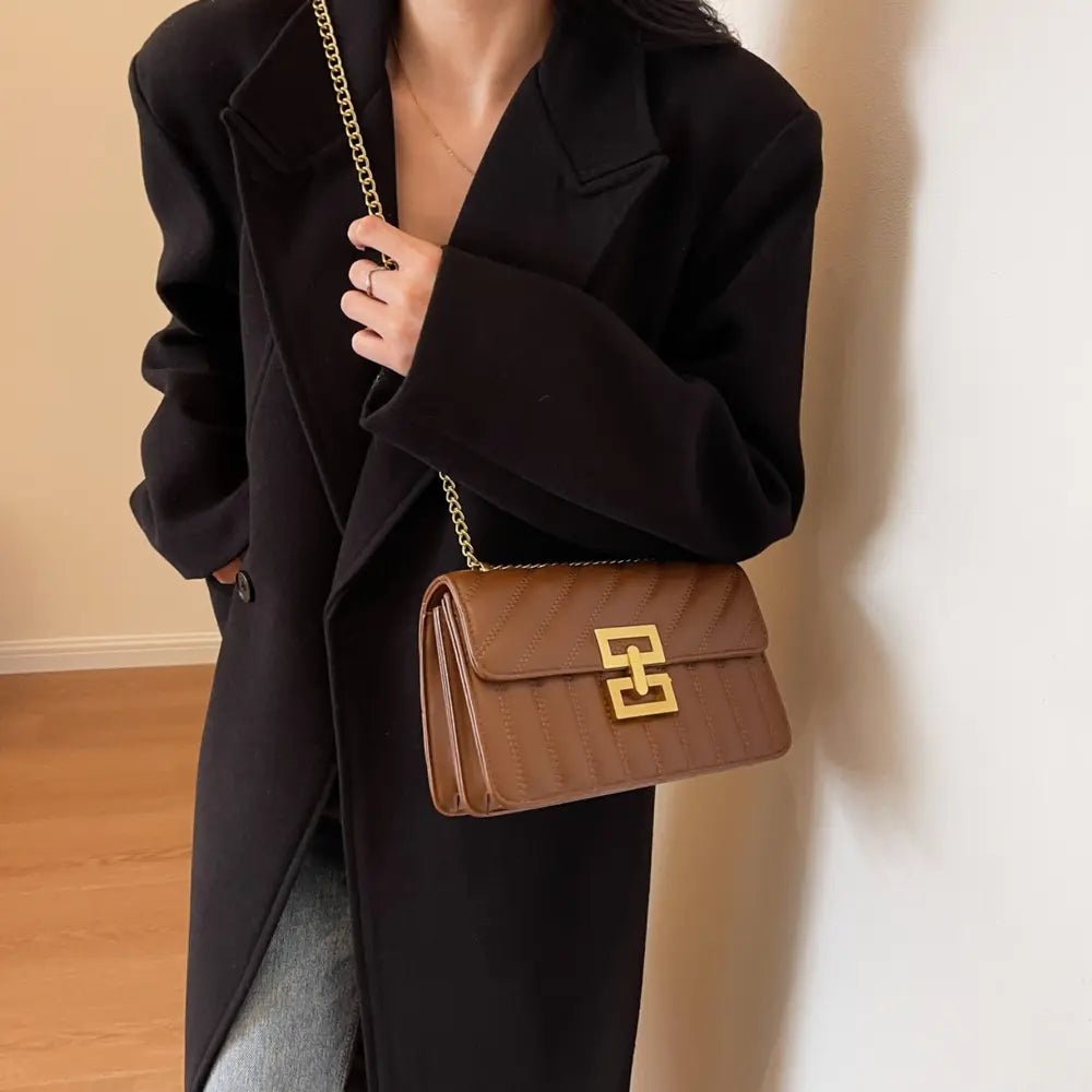 Brown crossbody bag with gold chain strap, flap closure, and square logo clasp.