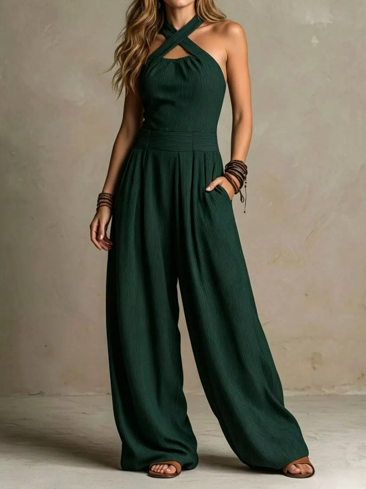 Dark green halter-neck wide-leg jumpsuit with sleeveless bodice and gathered waist.