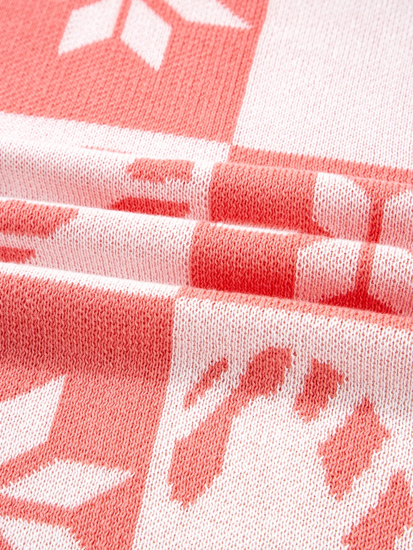 Burnt coral and white checker pattern knit fabric with snowflake and candy-cane motifs