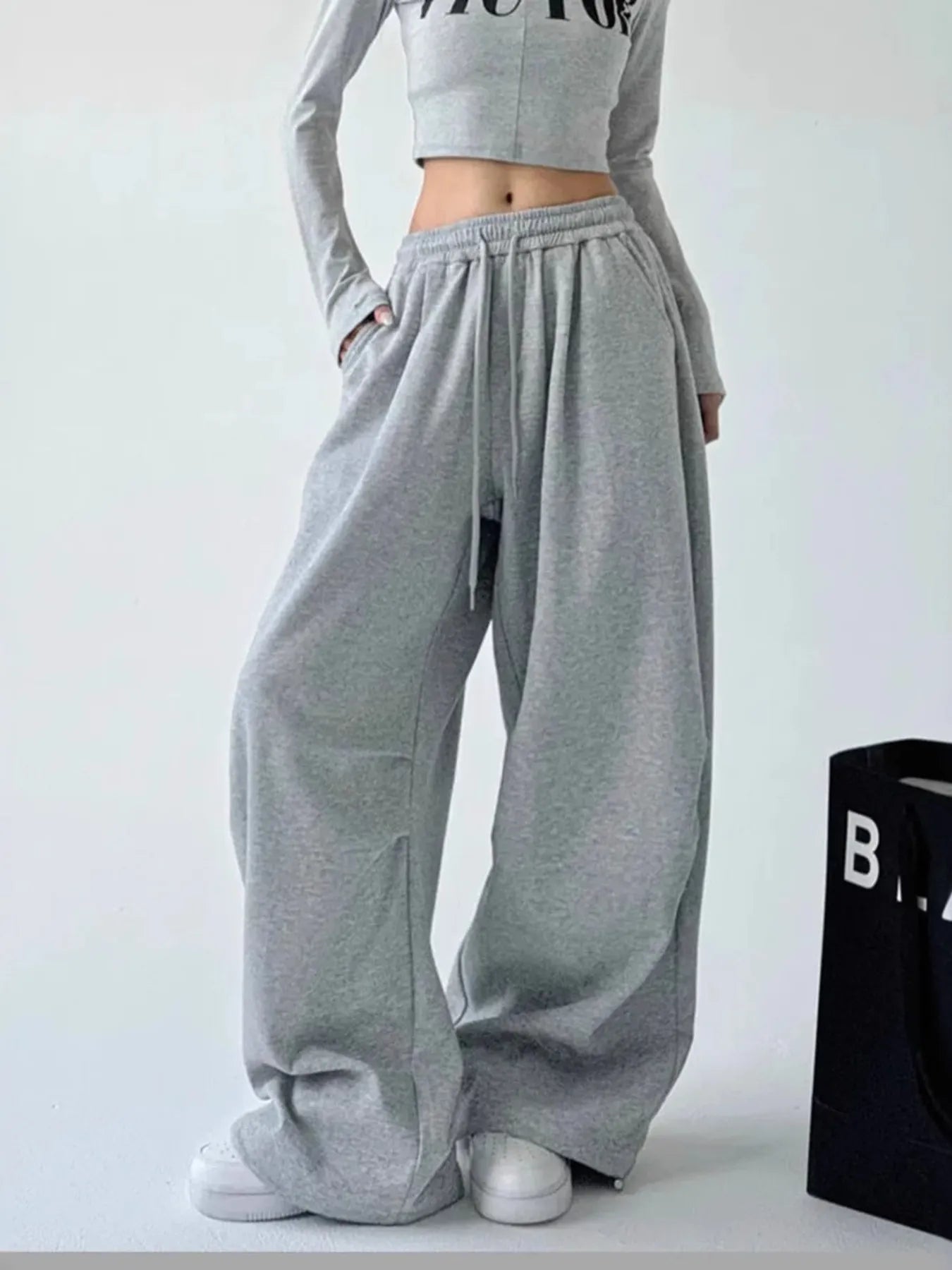 Dark gray oversized wide-leg drawstring pants with elastic waistband and gathered cuffs