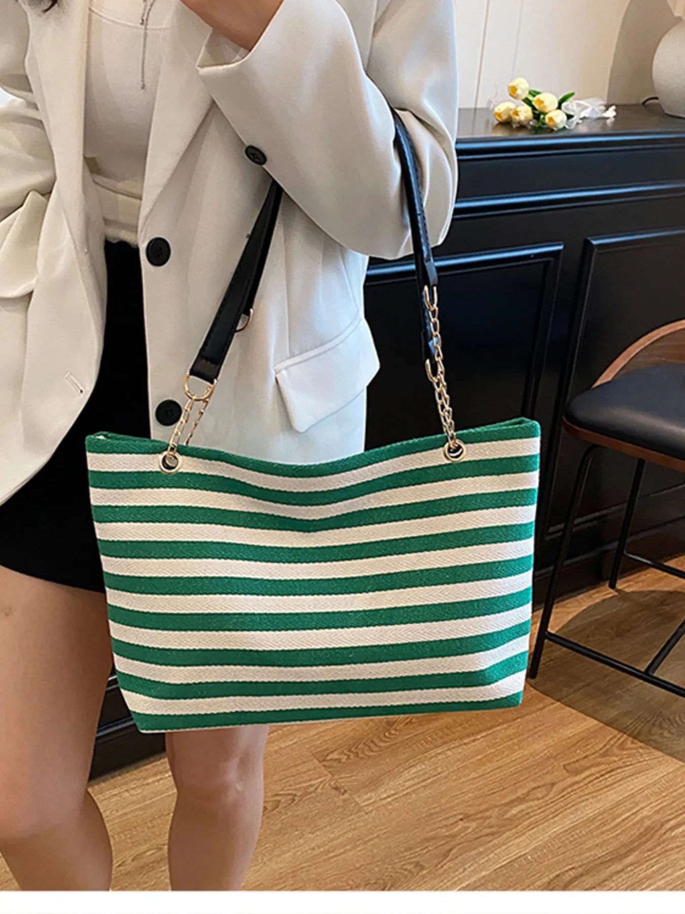 Green and white striped shoulder bag with gold chain handles and black strap accents.