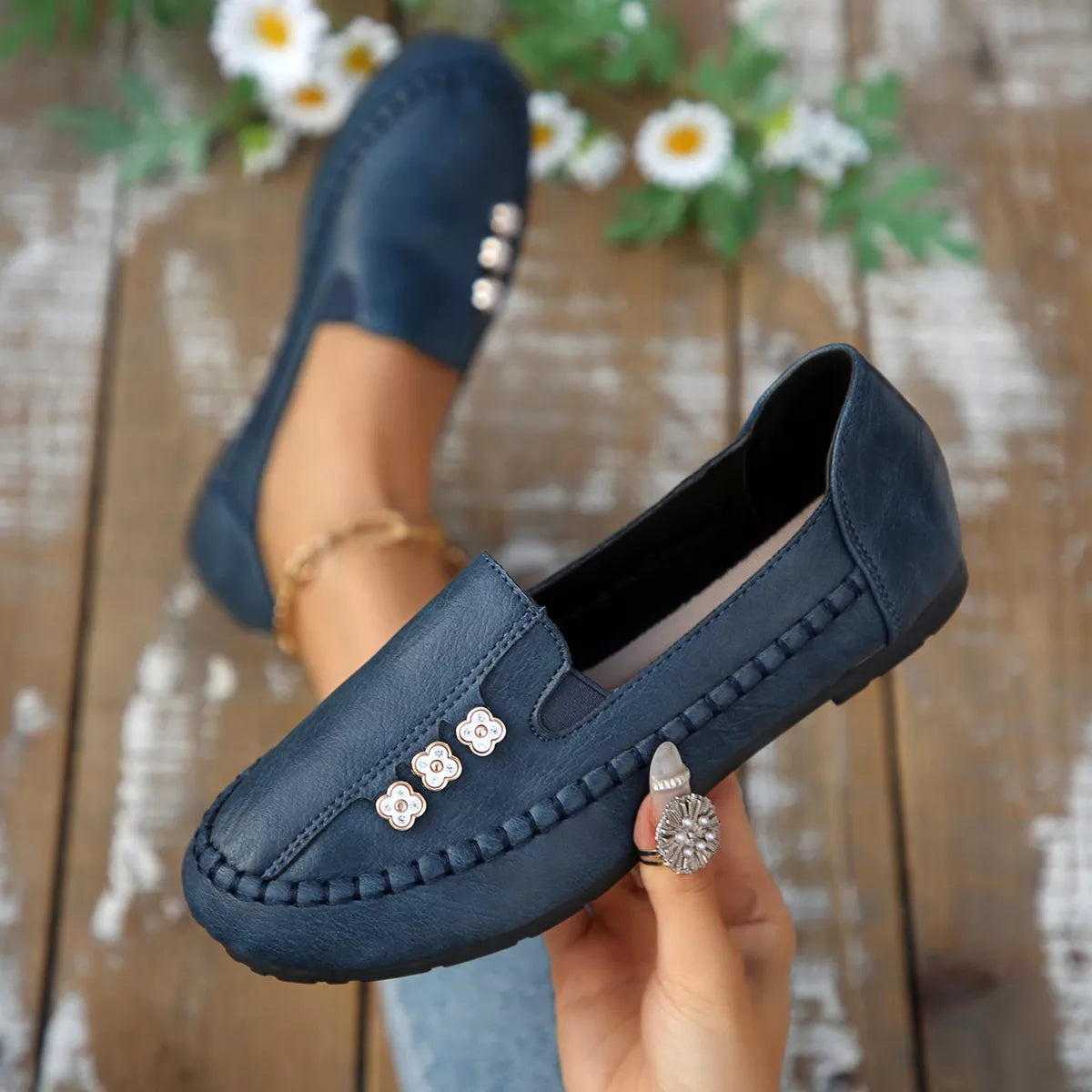 Dark blue round-toe slip-on flats with floral charms on the front vamp