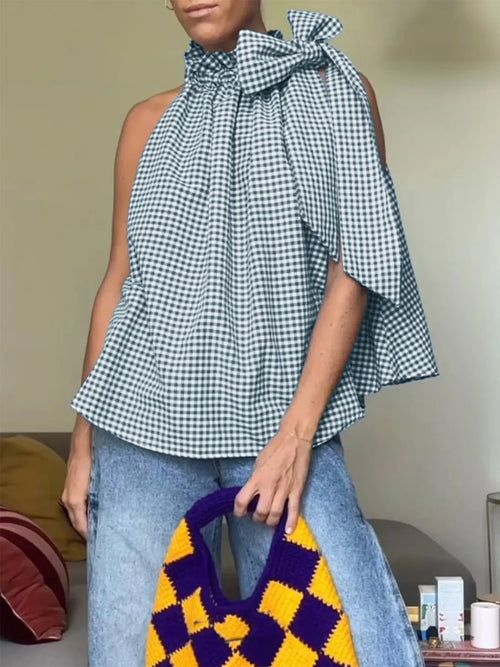Sleeveless gingham top with high ruffled neckline and tied bow at shoulder, dark and white plaid