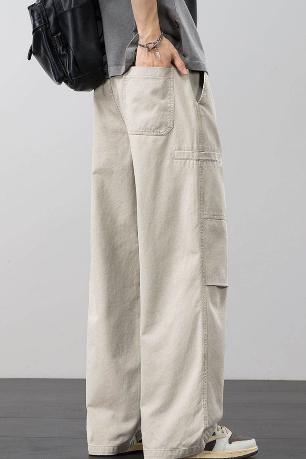 Beige wide-leg cargo pants with drawstring waist and flap side cargo pocket detail.