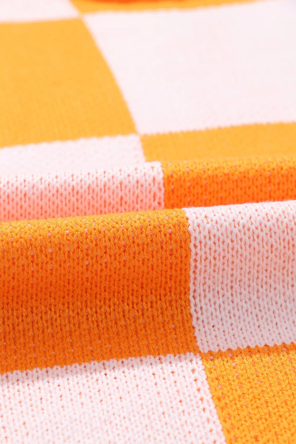 Checkered knit sweater with exposed seam detail, orange and white block pattern.