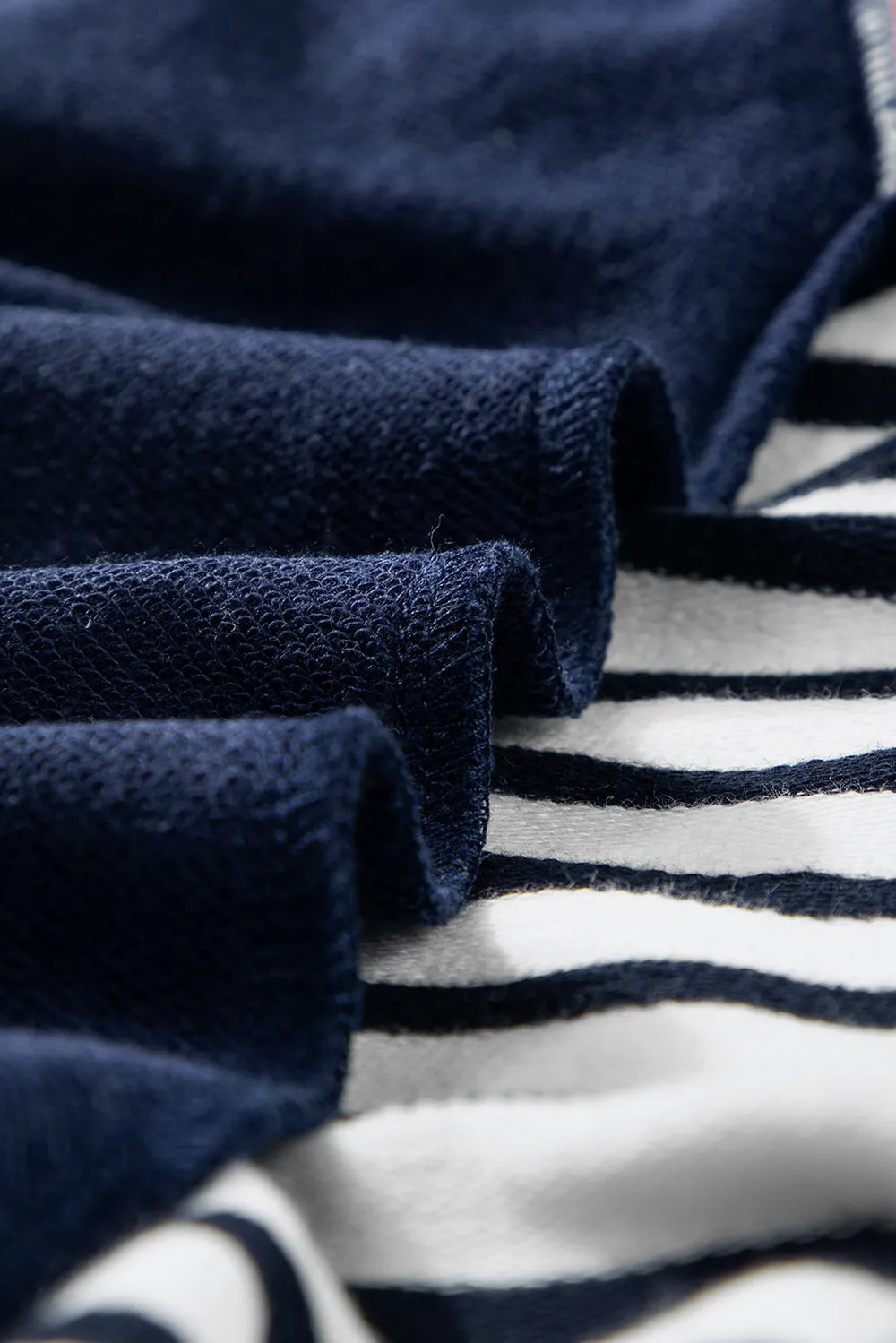 Navy knit sweatshirt fabric with white striped panel detail and visible seam stitching