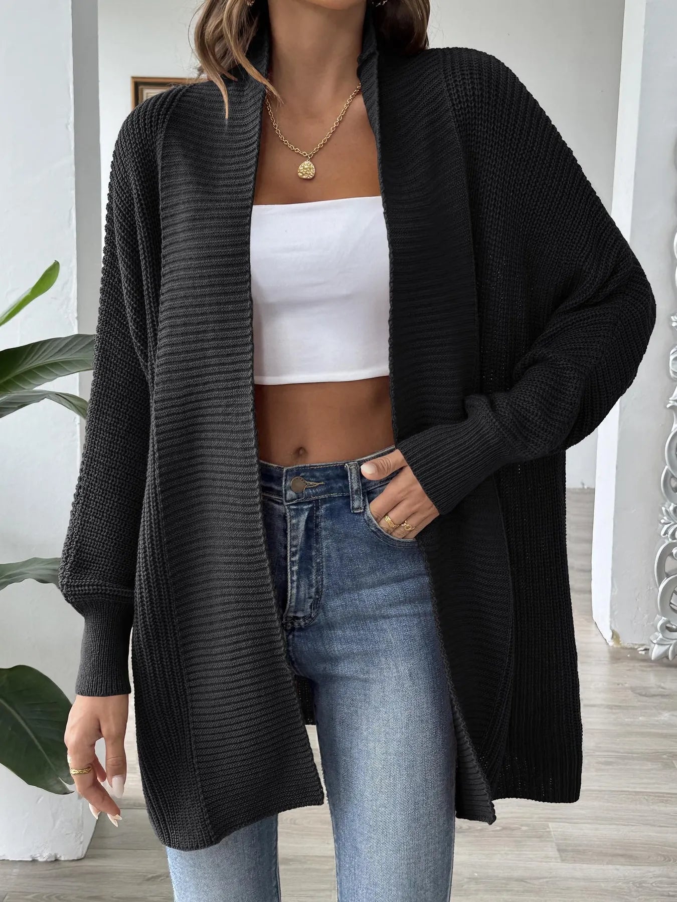 Black knit open-front cardigan with long sleeves, draped hem, chunky ribbed knit