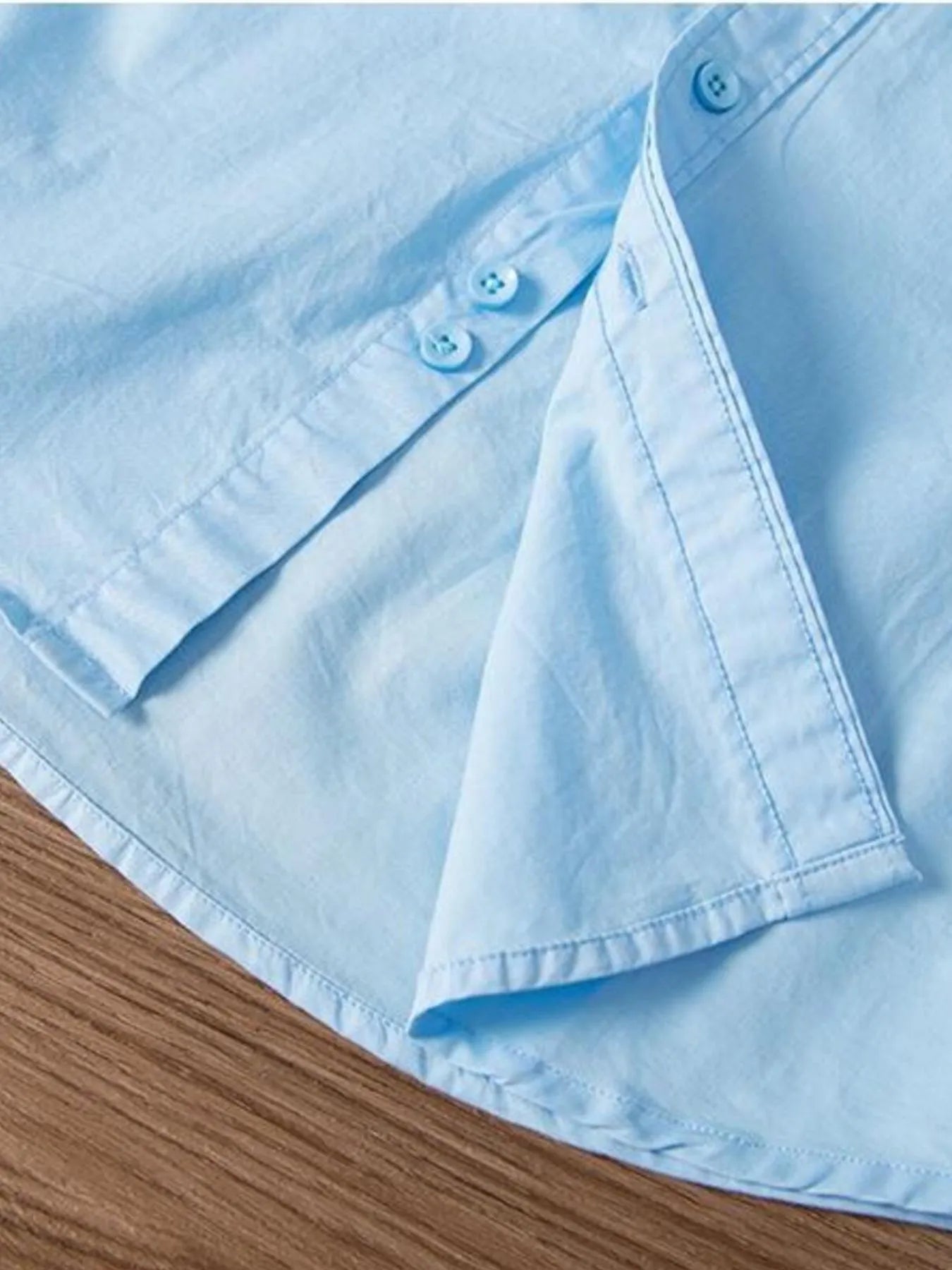Light blue button-up shirt collar and sleeve placket with matching buttons