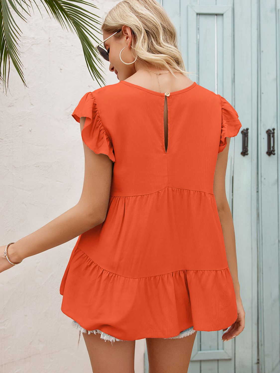 Orange tiered blouse from back with keyhole cutout and tiered ruffle hem