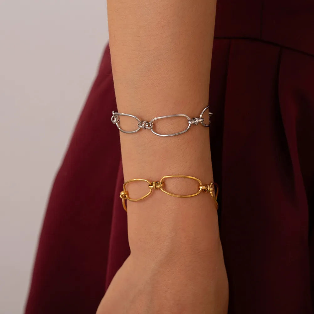 Chain bracelet pair on wrist: silver bracelet above gold bracelet with oval links