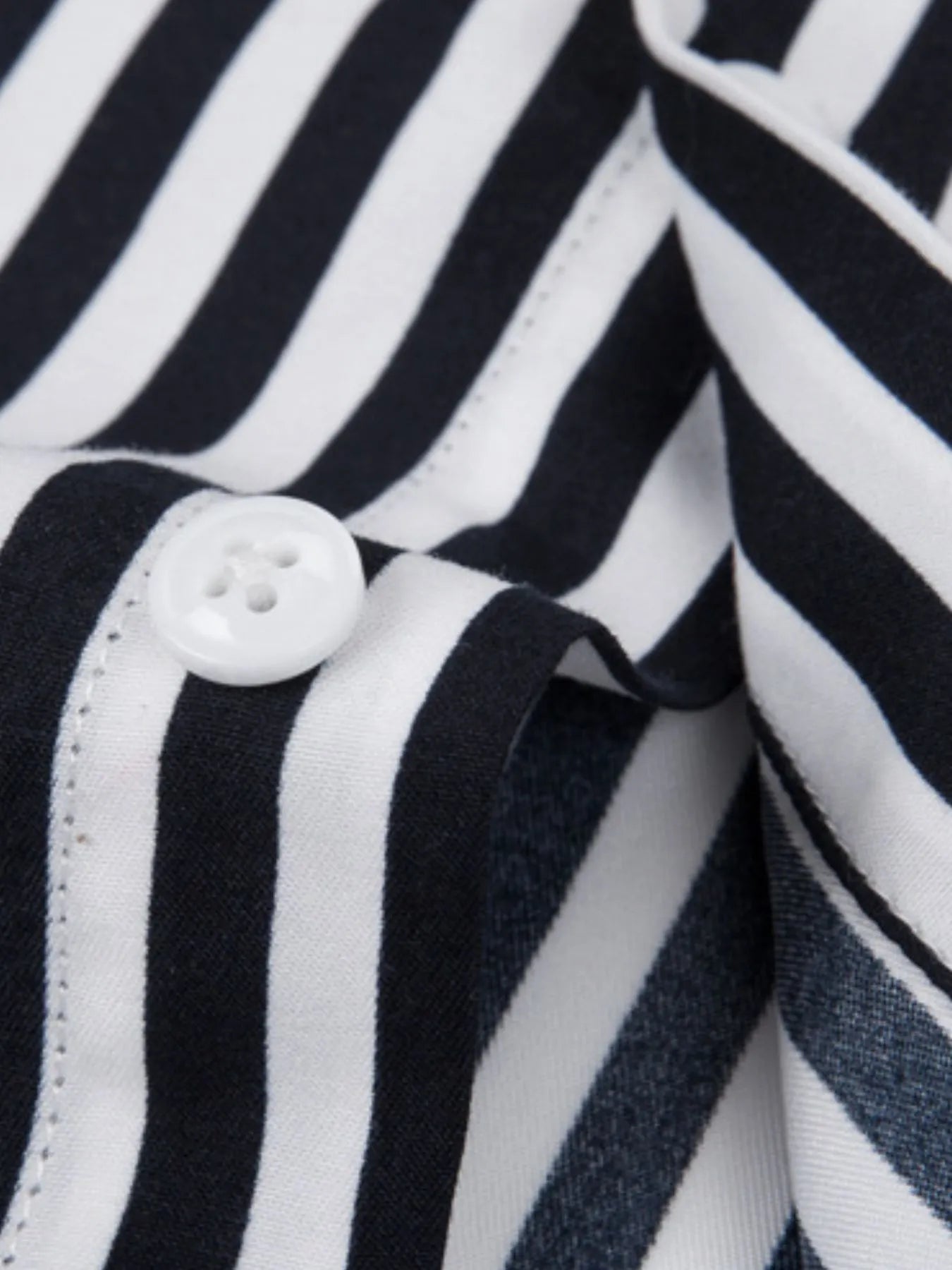 Striped button-up shirt placket close-up, black and white stripes with white buttons