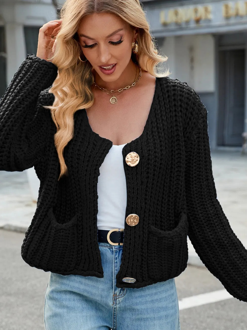 Black knit cardigan with round neckline, button front, and two front pockets