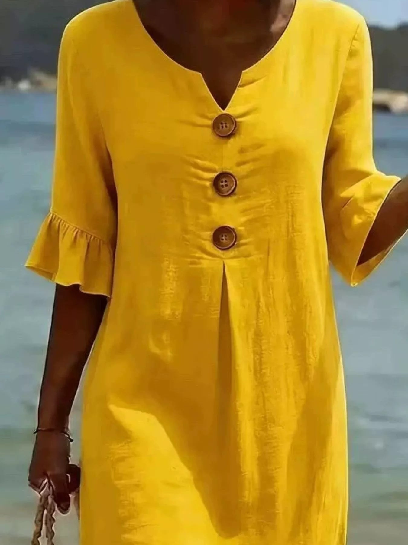 Yellow button-front dress close-up with V-neck and three wood-look buttons, ruffle cuffs