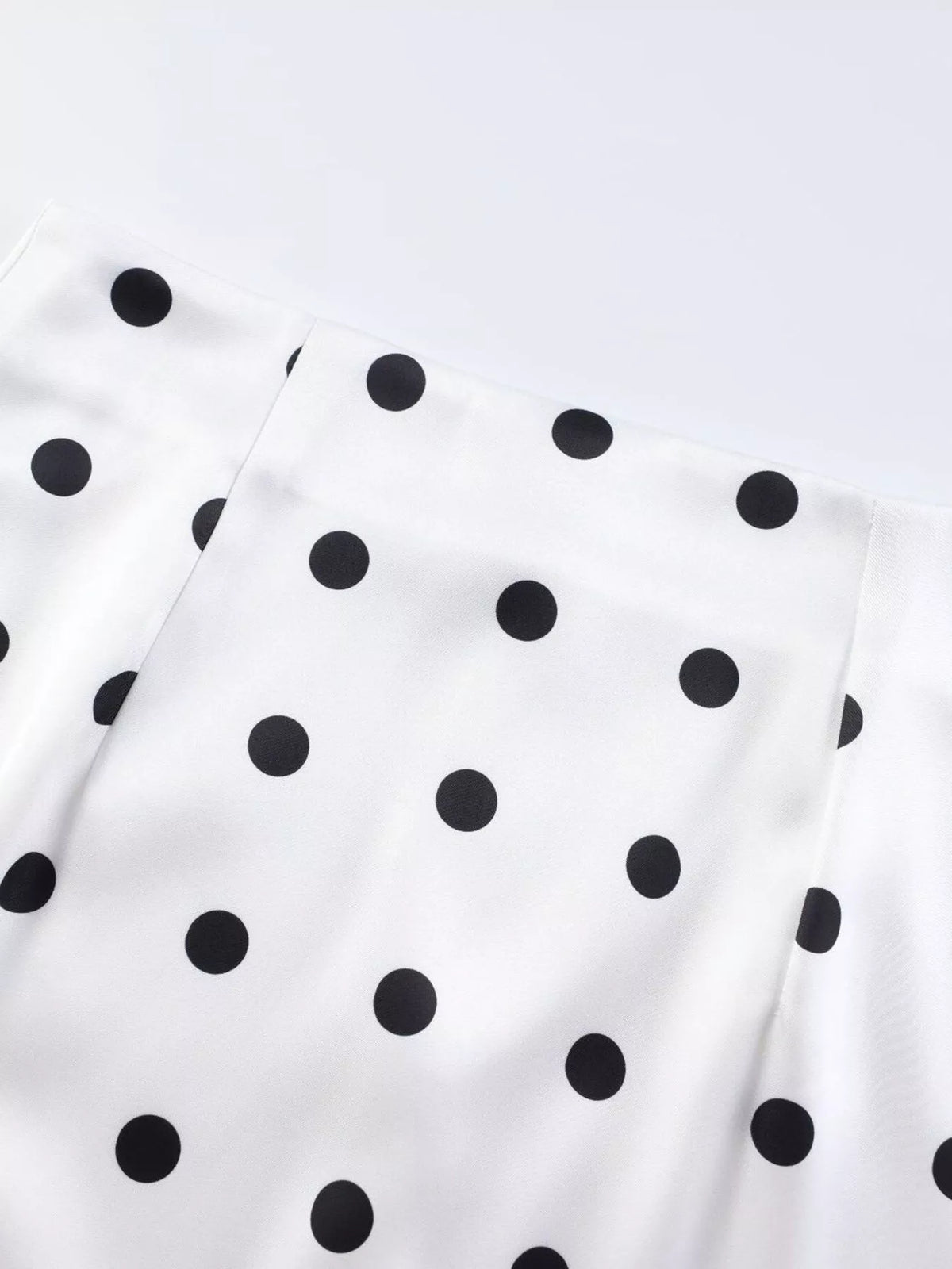 White fabric with scattered black polka dots, smooth surface