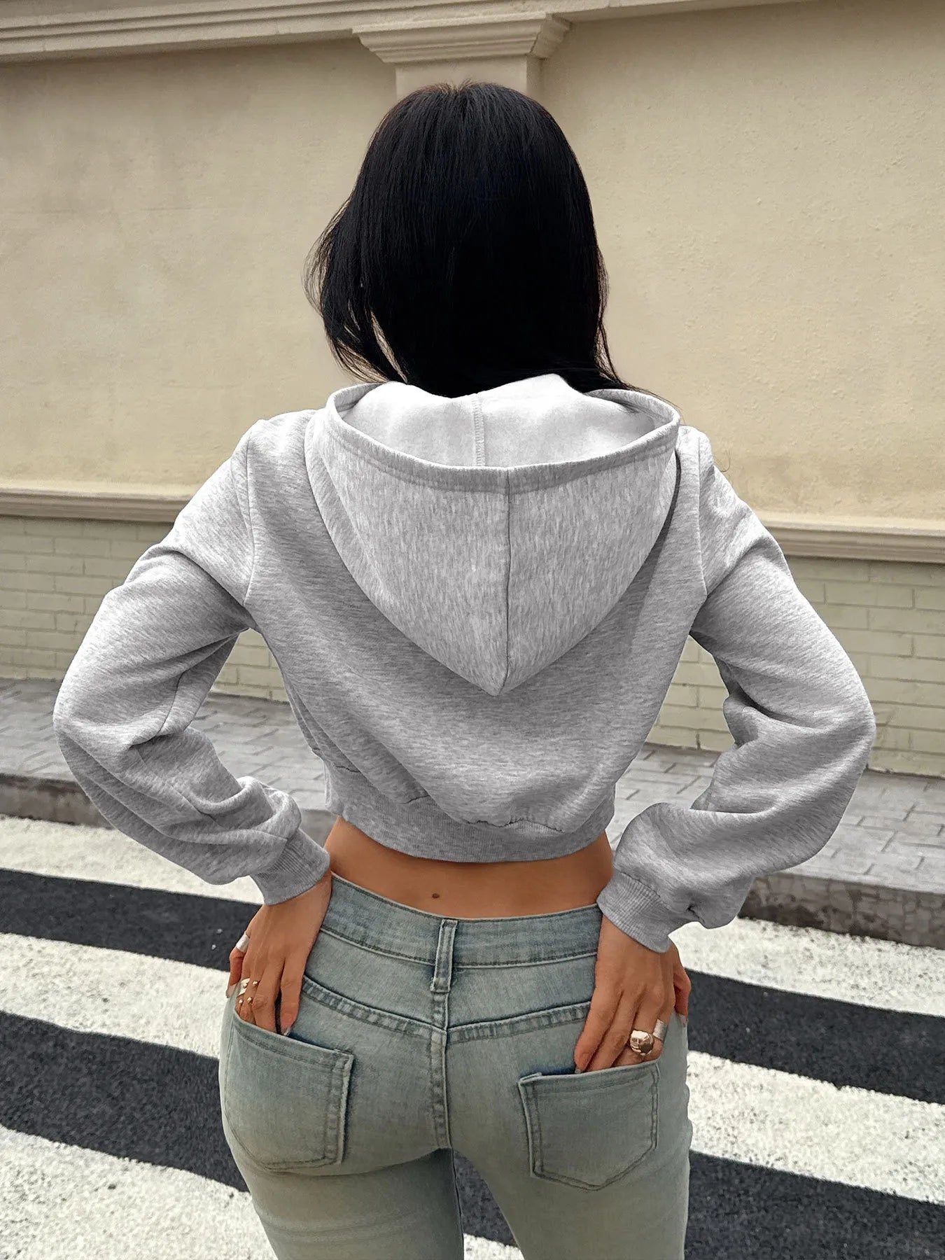 Light gray cropped zip-up hoodie from back view with hood and ribbed waistband