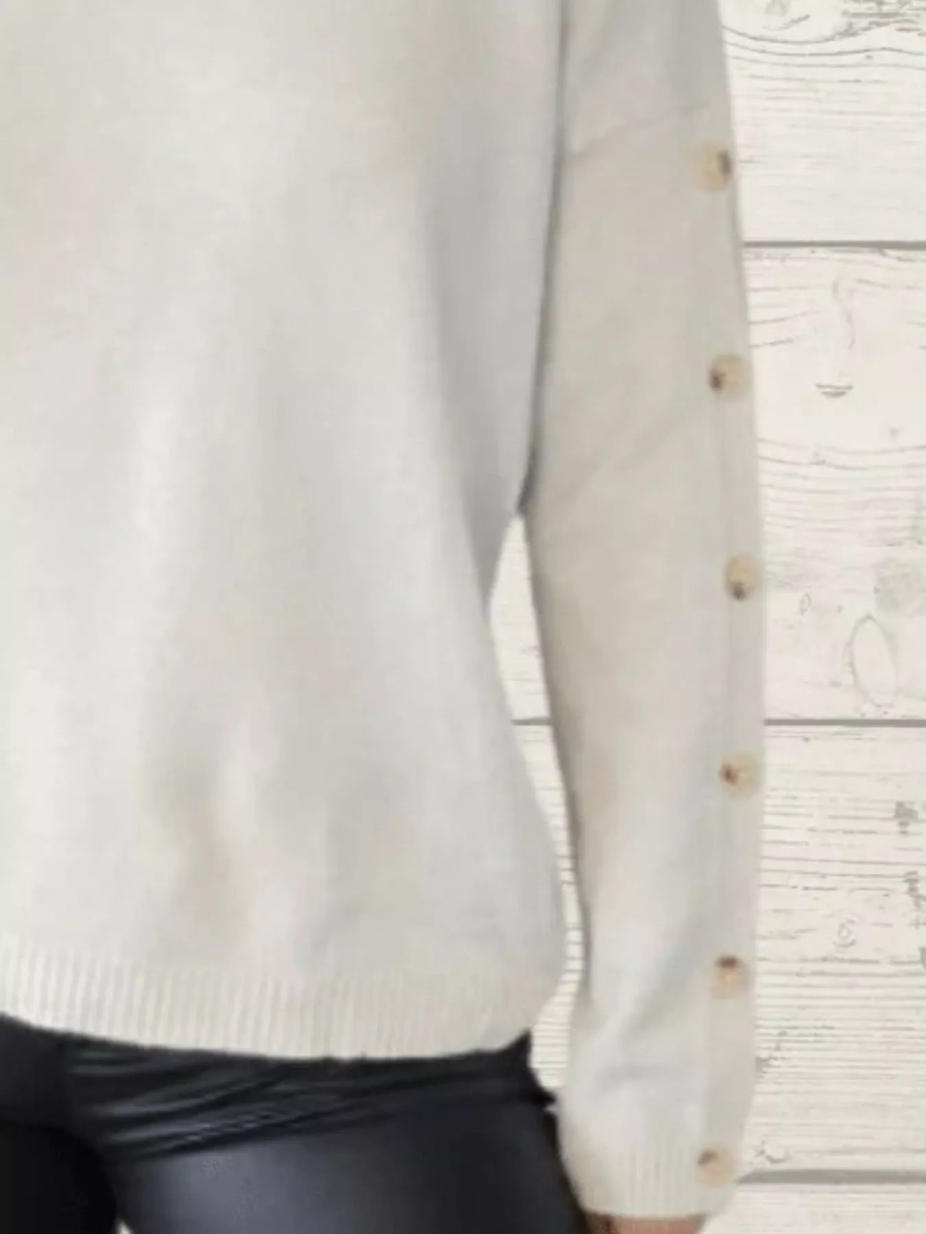 White long-sleeve turtleneck sweater with buttoned cuffs and ribbed hem