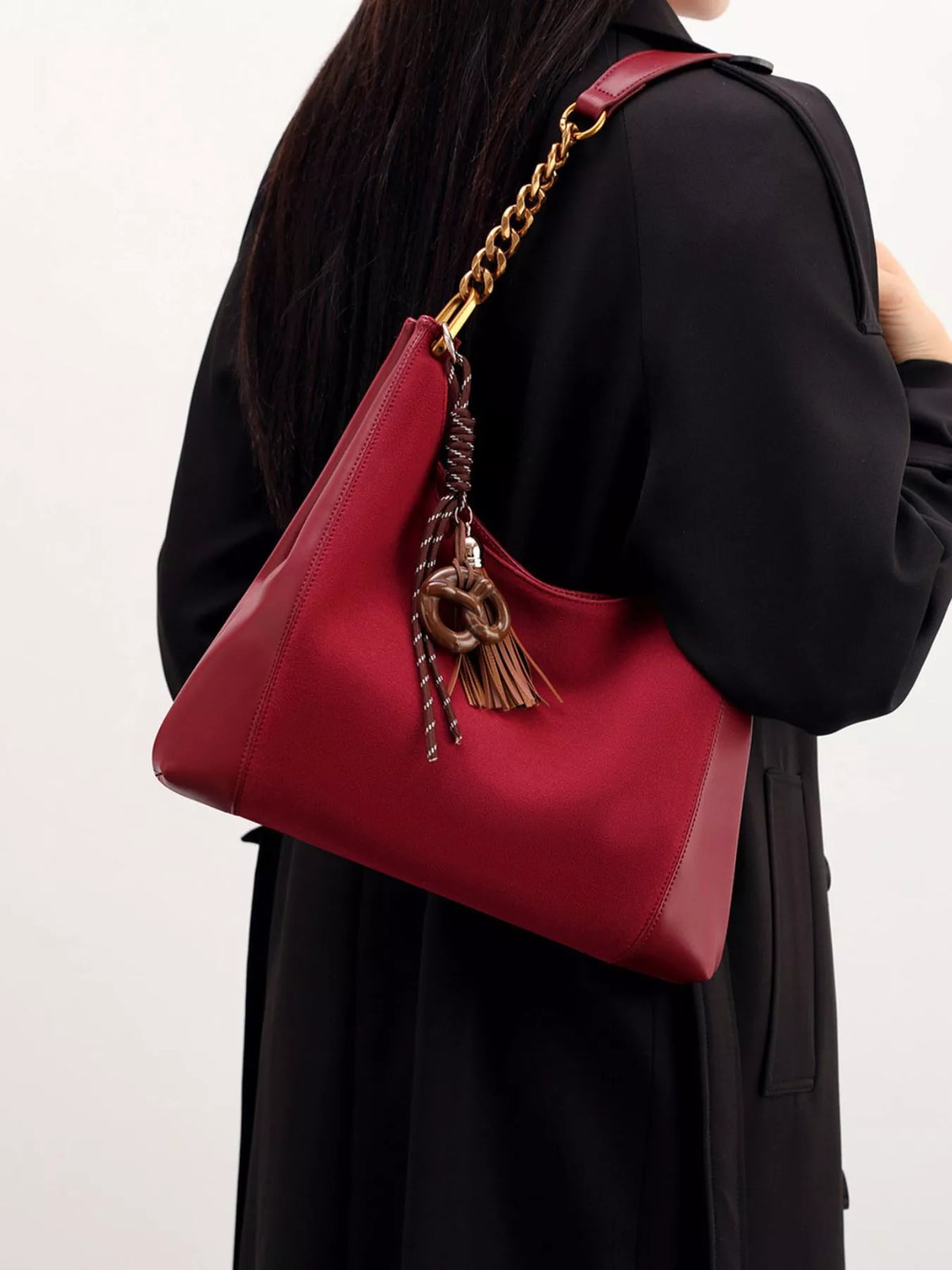 Wine red suede shoulder bag with gold chain strap and tassel, back-side view.