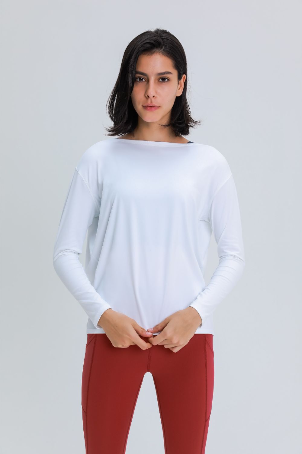 Loose fit active top in white, long sleeves and relaxed drape at waist.