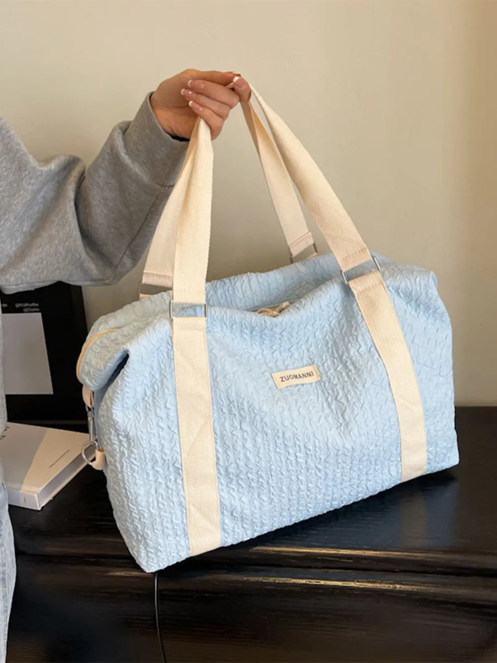 Light blue textured duffle travel bag with tan straps and side zipper