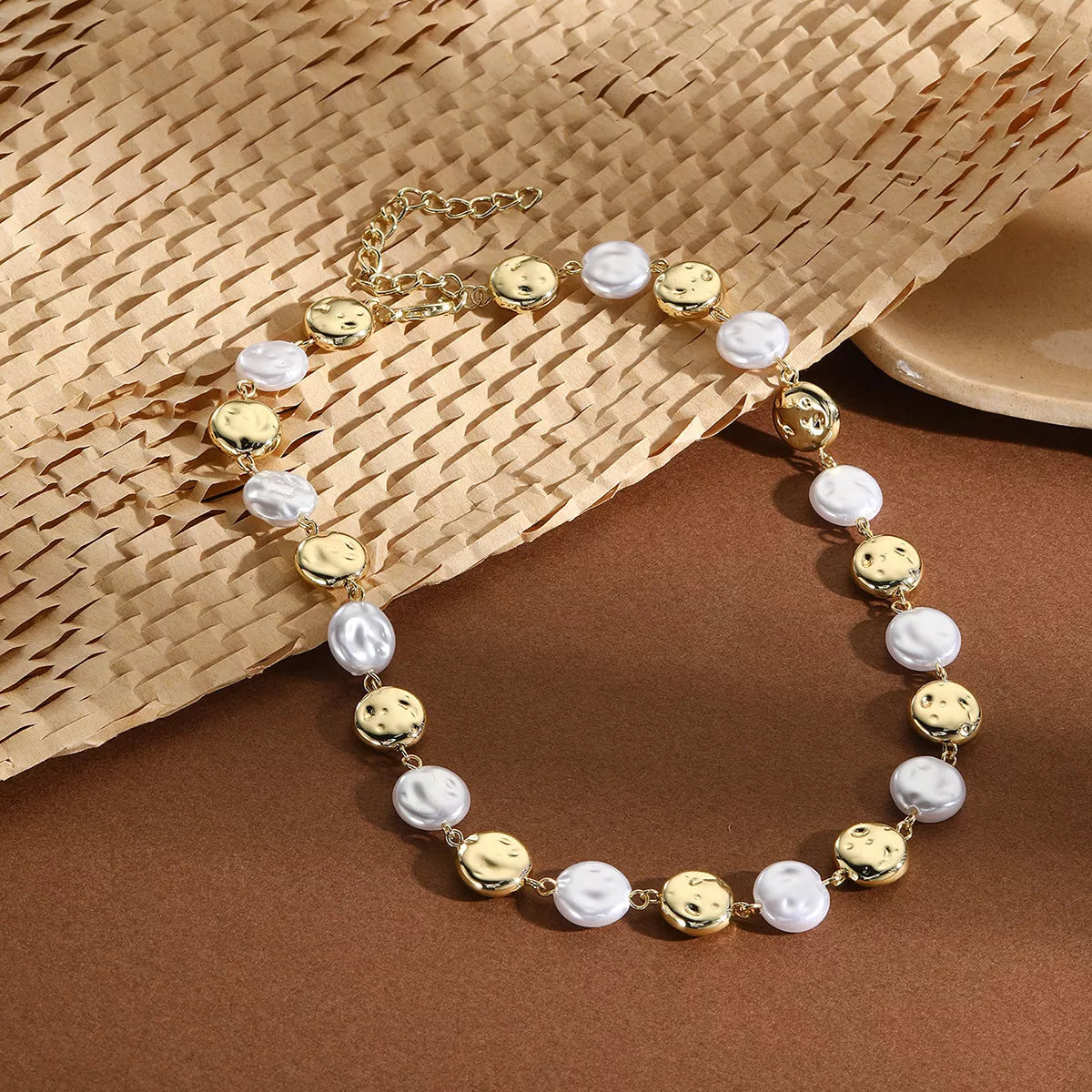Pearl chain necklace with gold-tone round beads and white pearl beads, flat lay