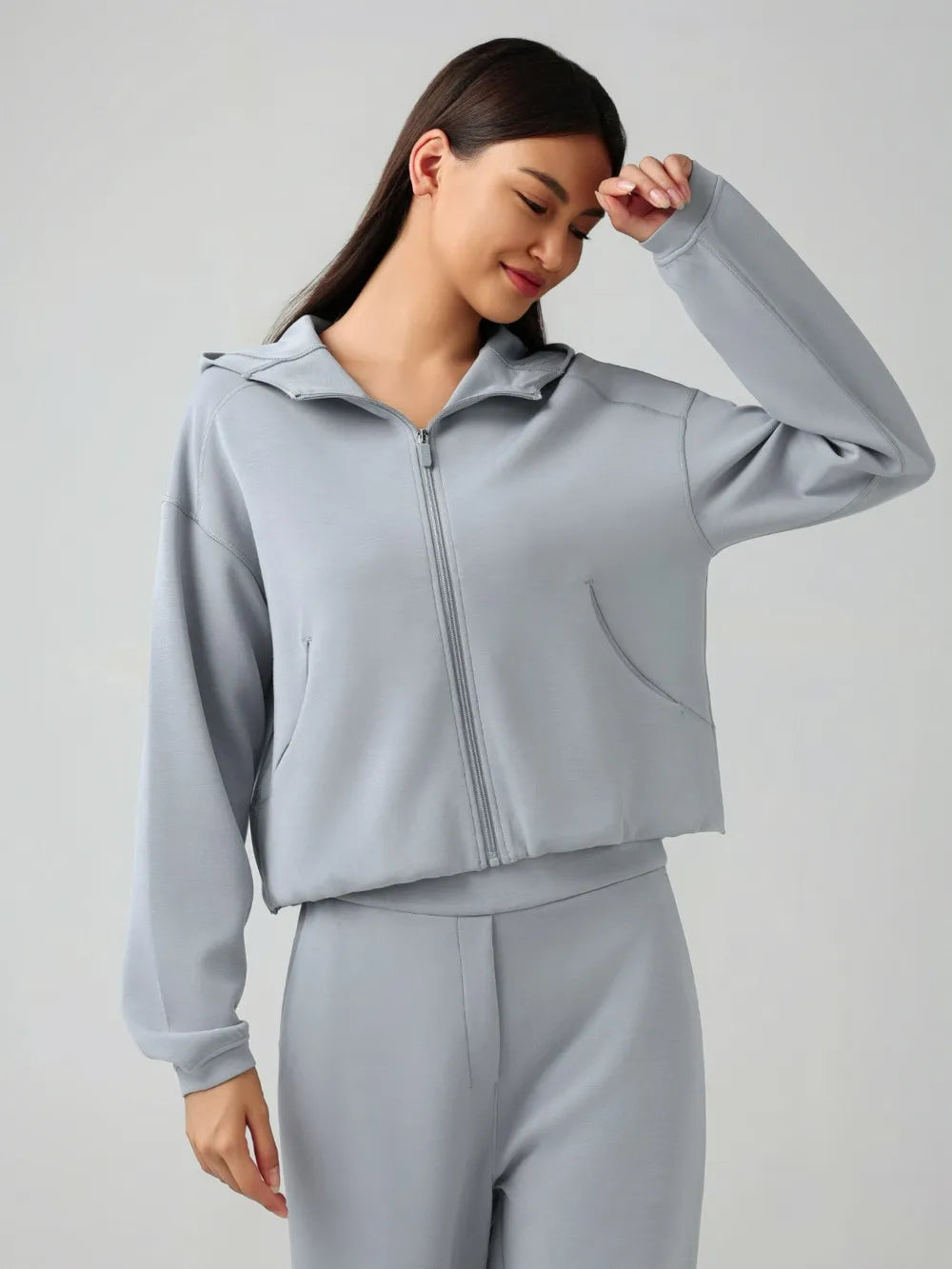 Light blue zip-up active hoodie with hood and front zipper, side view with raised hand