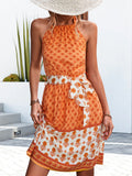 Orange floral halter neck dress with tie waist bow detail and white patterned tiered hem