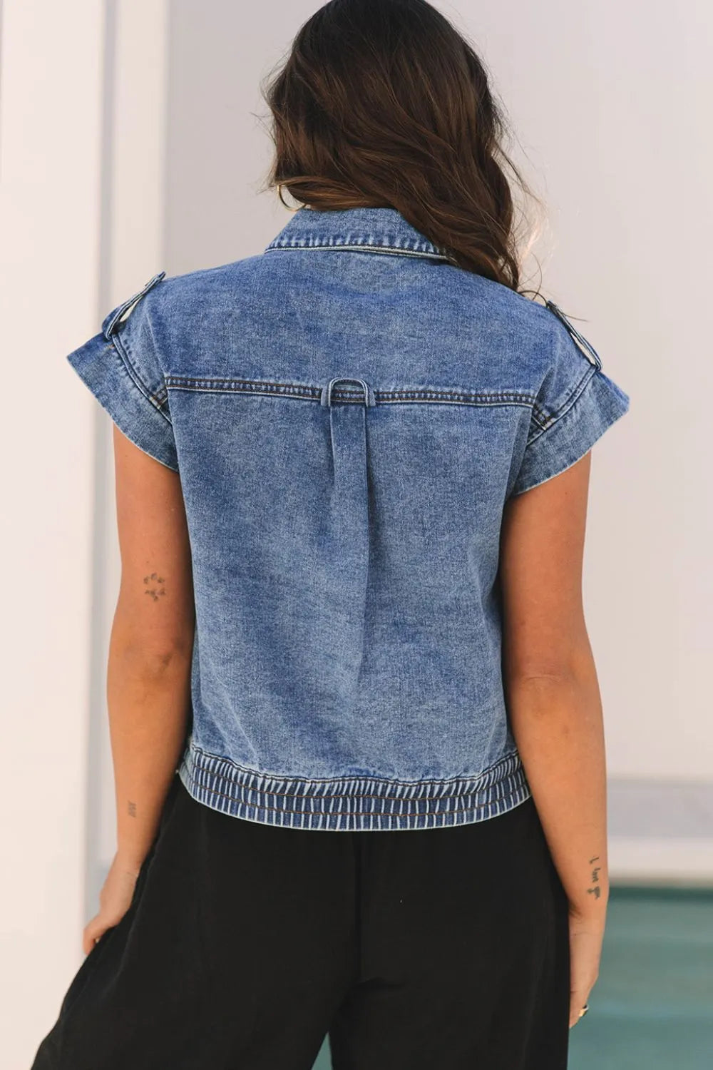 Medium-wash denim button-up cap sleeve jacket, back view with yoke seam detail