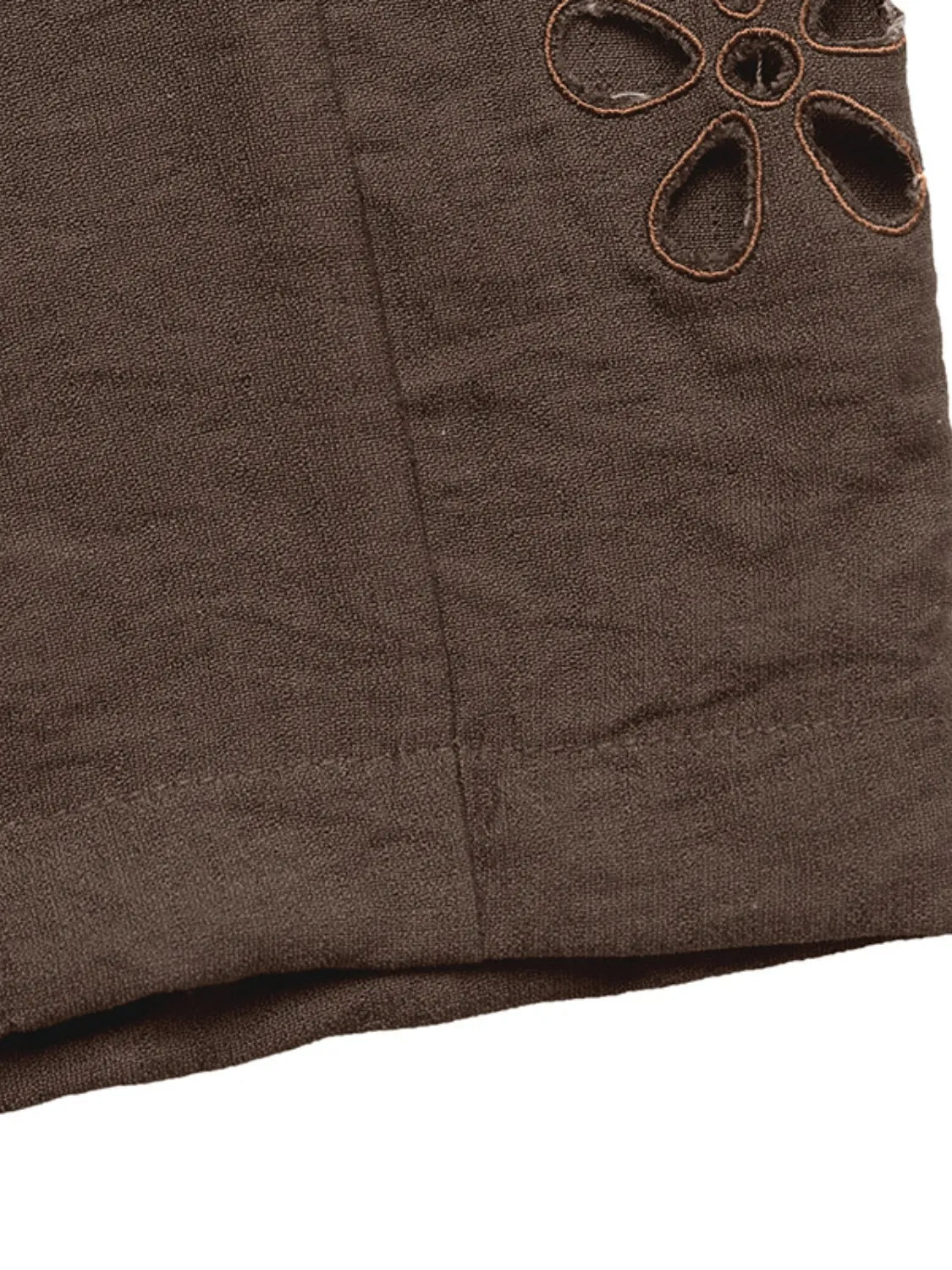 Dark brown pants fabric with stitched seam and small floral appliqué