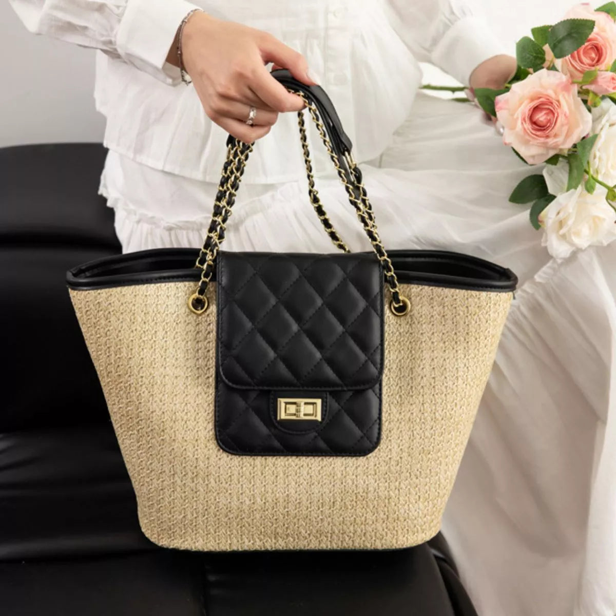 Woven straw tote bag with black quilted front pocket, top handles, and chain strap