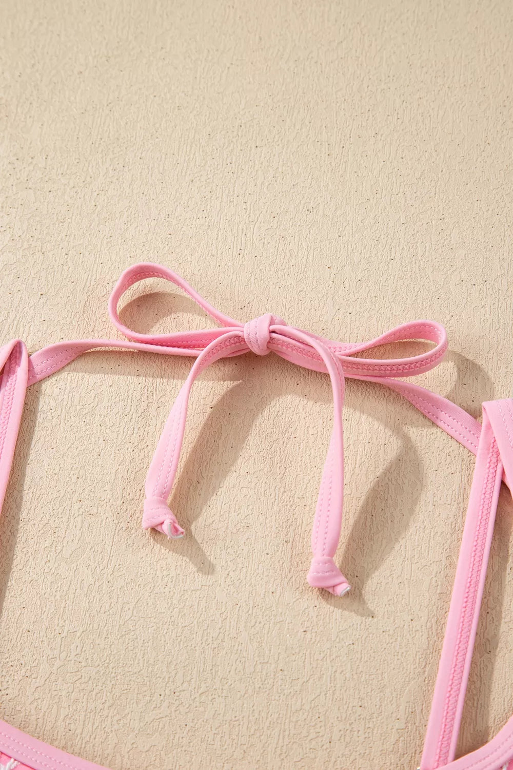 Blush pink halter swimsuit straps with bow at neckline and open back cutout