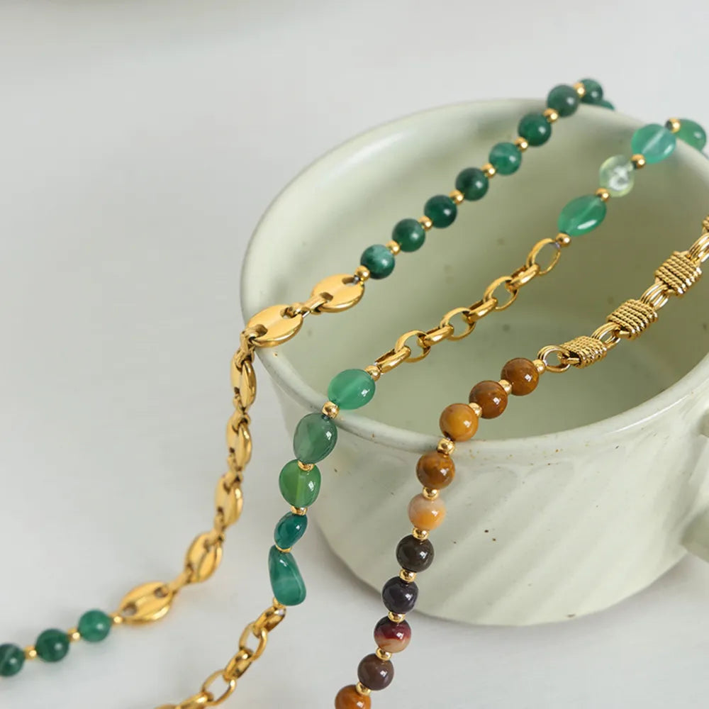 Layered beaded necklace with green, brown, and gold chain links in multiple strands