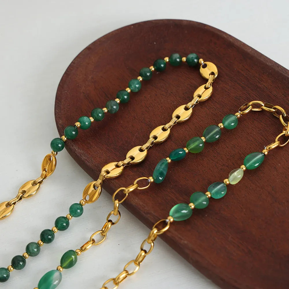 Beaded necklace with green round beads, gold oval links, and layered bracelet-style chains