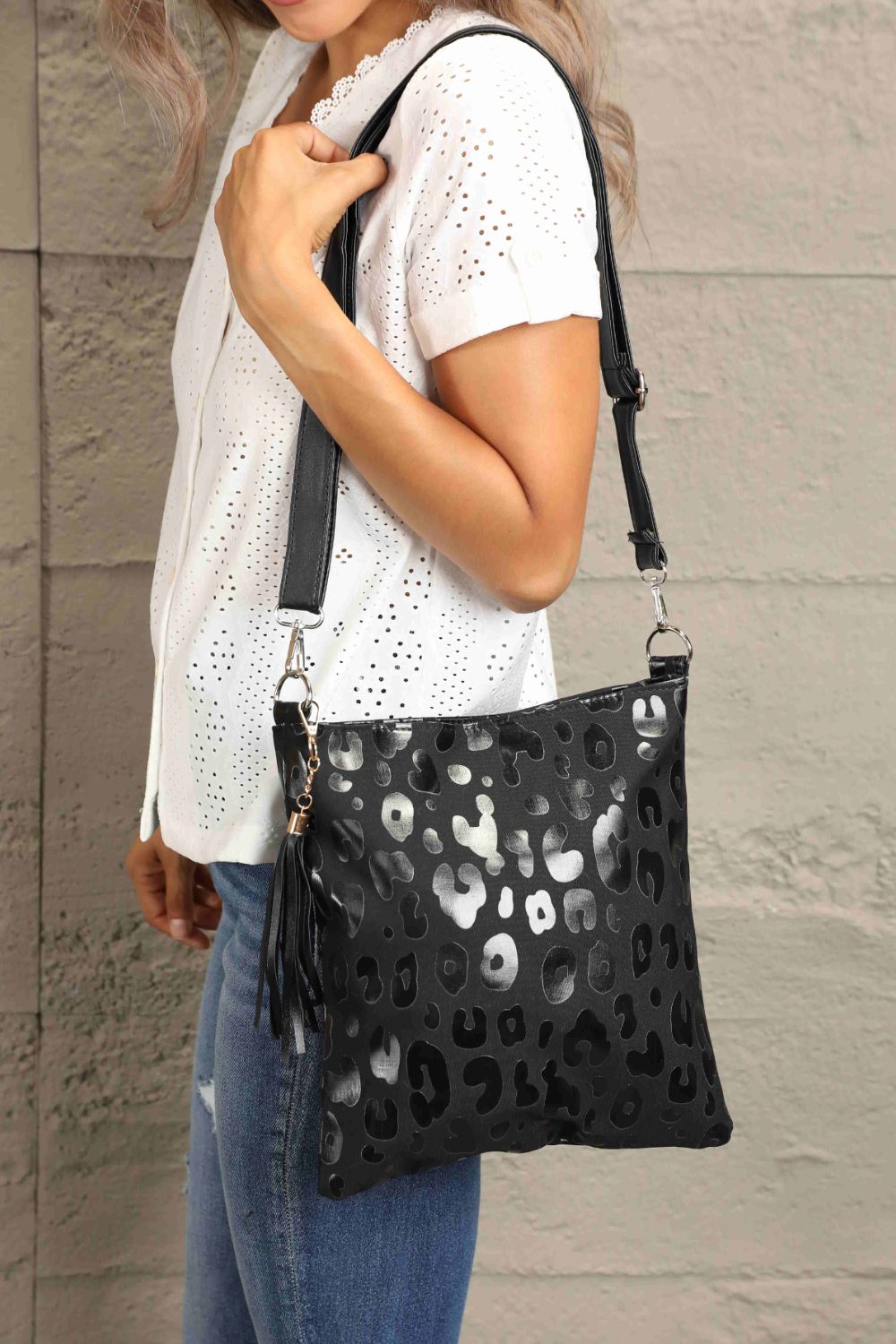 Black PU leather shoulder bag with perforated heart pattern, tassel and gold hardware