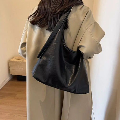 Black adjustable-strap shoulder bag with slouchy hobo silhouette and curved top opening