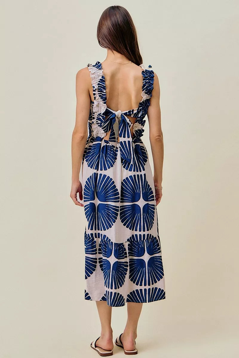 Back view of navy and white abstract print tiered midi dress with smocked waist detail