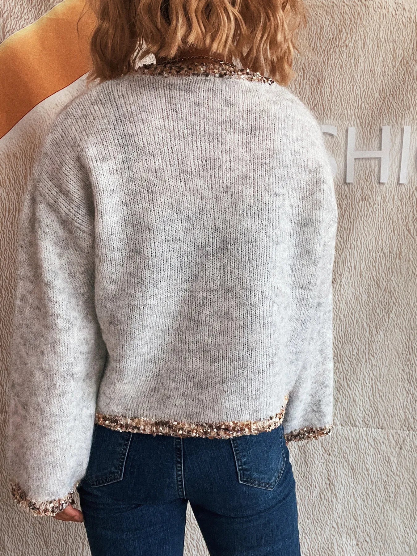 Light gray cropped knit sweater, back view, with sparkly trim across hem and sleeves