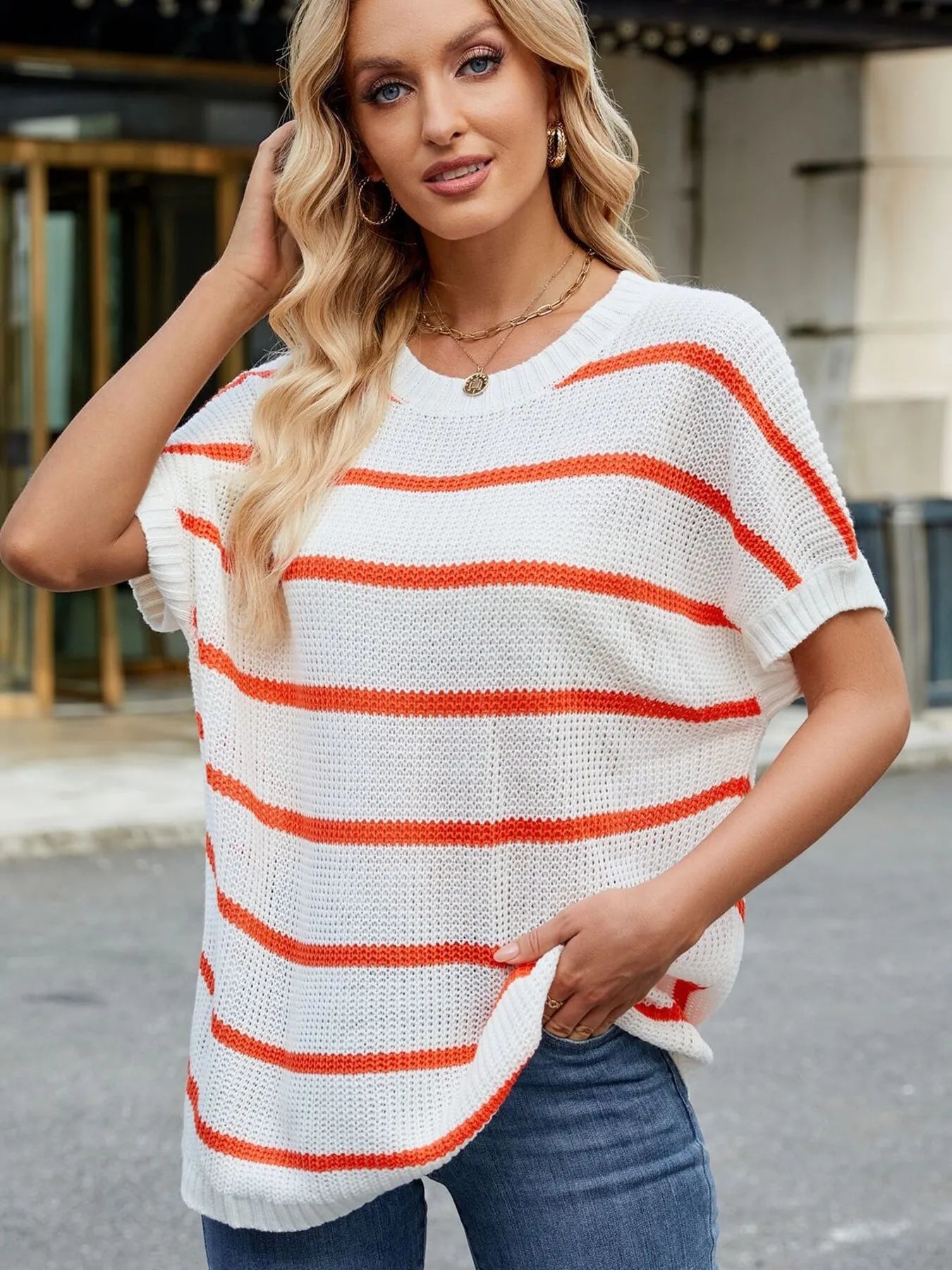 Orange-and-white striped knit sweater with loose oversized fit and wide short sleeves